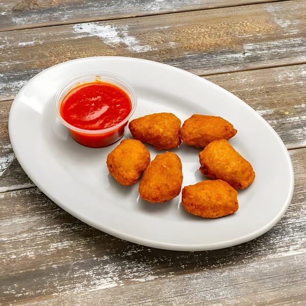 Golden-brown fried appetizers and a cup of red marinara sauce on a white oval plate.