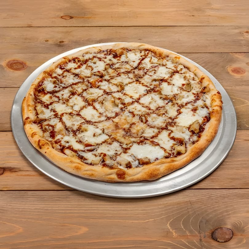 A whole Roma Pizza Restaurant BBQ chicken pizza with white cheese and sauce drizzle on a wooden table.